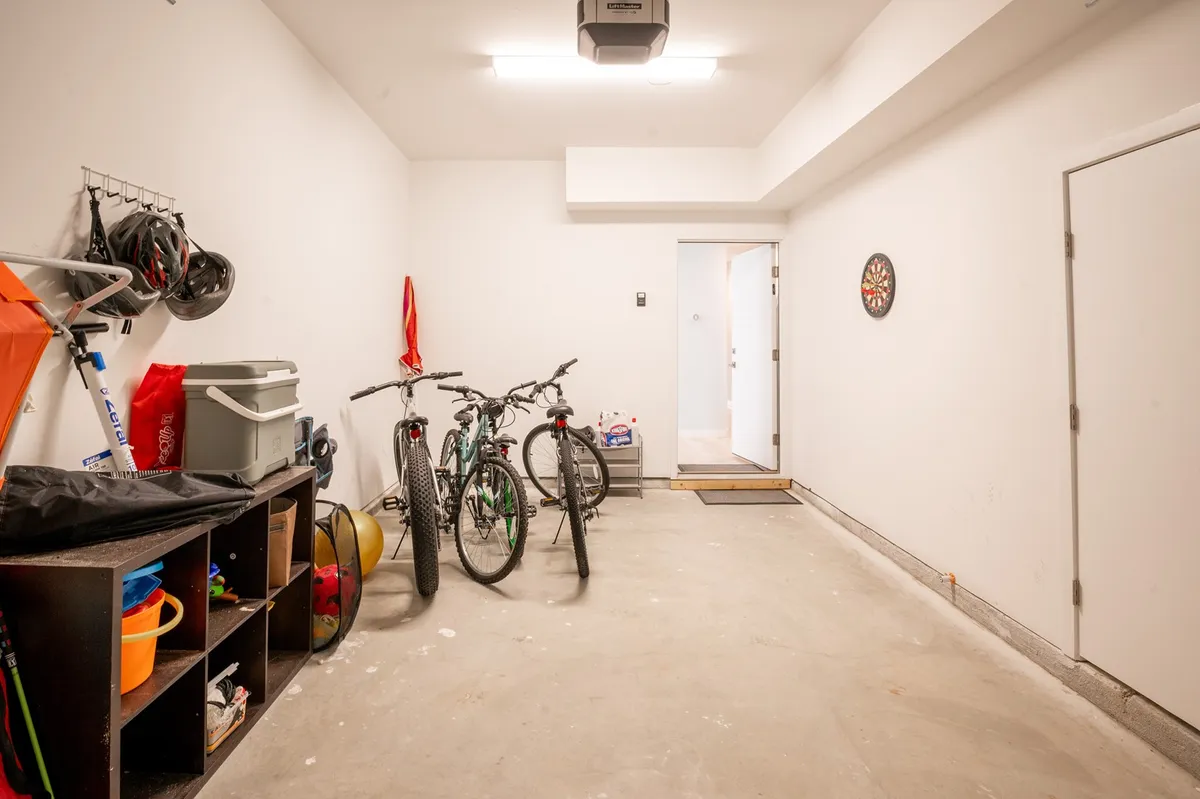 A practical storage space featuring bicycles, storage units, and a dartboard—ideal for prepping for outdoor adventures or family leisure time. The presence of bikes hints at local exploration and the active lifestyle of Carolina Beach.