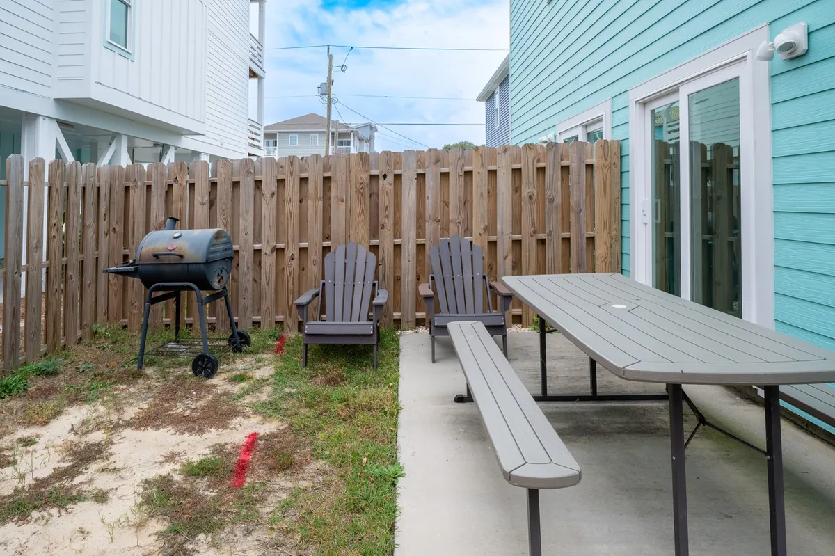 This image features a backyard setup with a grill, Adirondack chairs, and a picnic table, providing a relaxed atmosphere perfect for outdoor dining and social gatherings.