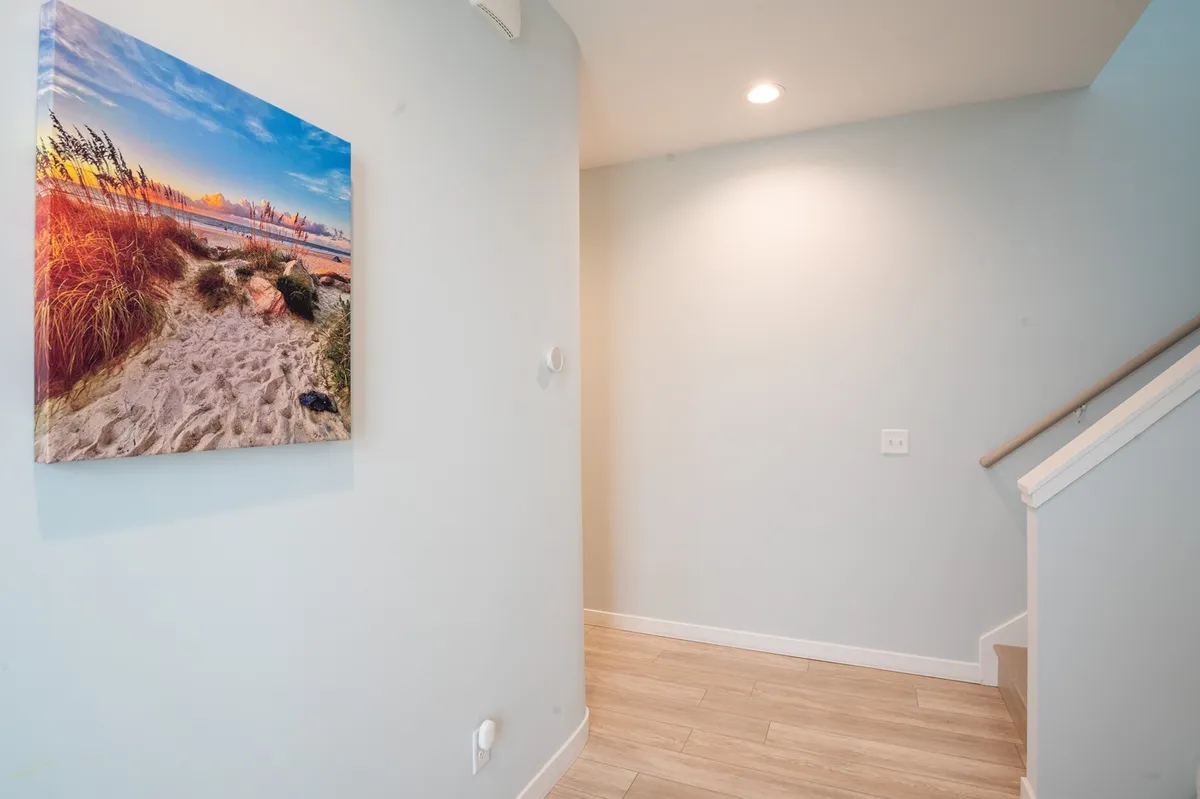 The staircase area accented with beach-themed artwork, inviting visitors further into the home while subtly referencing the coastal atmosphere. The composition suggests movement and anticipation, echoing the excitement of upcoming local festivities.