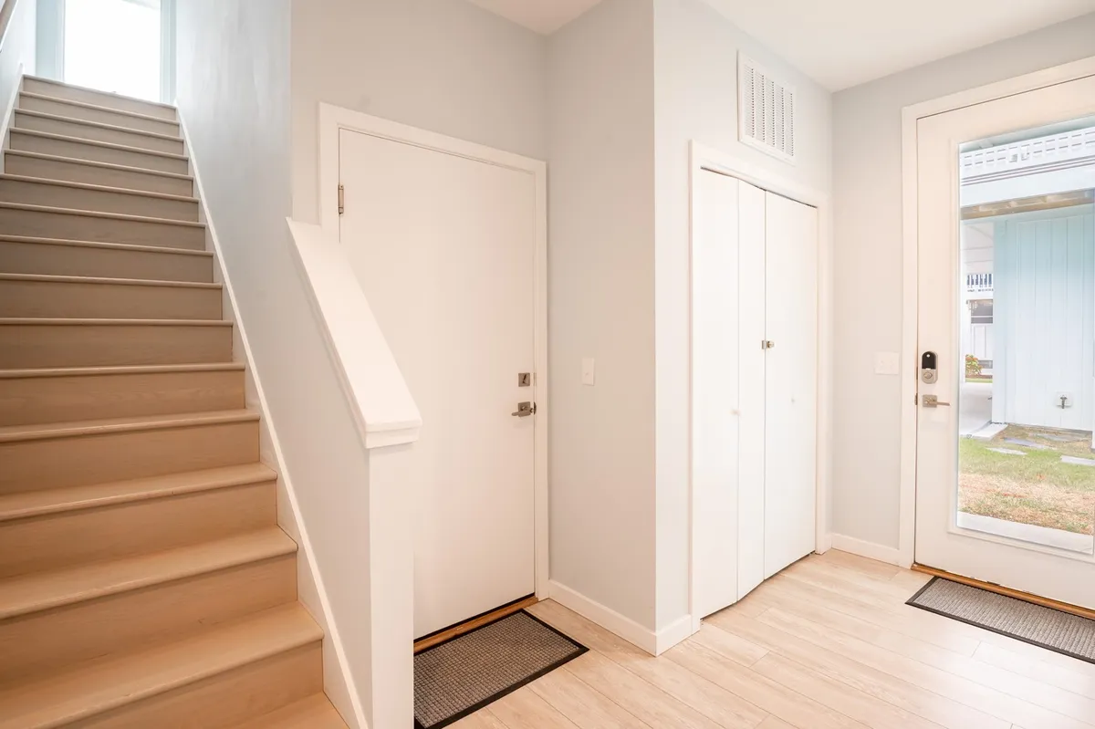 A view from the entryway looking toward the staircase and front door, capturing the transition from outside to inside. The image offers a sense of arrival and hints at the home’s connection to the broader Carolina Beach community just beyond the doorstep.